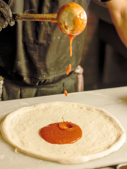 Painting the canvas of flavor, one dollop of sauce at a time. This artistic shot highlights the craft and care that goes into making each pizza.