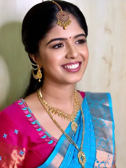 A lovely, happy shot of Priya for her engagement. The makeup is fresh and dewy, with a lip color that complements her bright blue and pink saree.