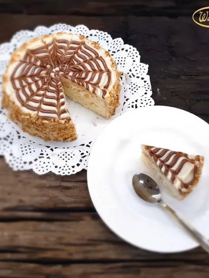 A slice of our classic Butterscotch Cake, served on a delicate doily. This cake has a light, nutty flavour, with crunchy butterscotch nougat mixed into the cream and a beautiful web-like pattern on top.