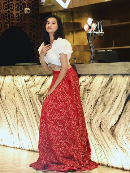 A full-length shot of the red and white Indo-Western lehenga. The combination of the traditional skirt and modern top creates a unique and stylish look.
