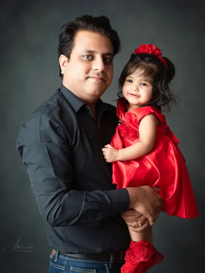 A sweet portrait of a father and his daughter, her red dress popping against the classic background.