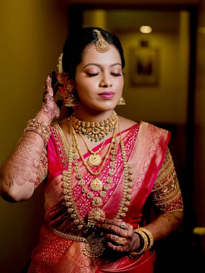 A candid moment of adjustment, showcasing the intricate details of her jewelry and the soft, glowing makeup.