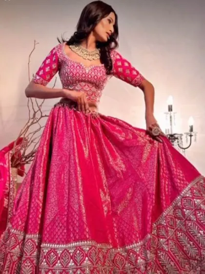 A full shot of the rani pink lehenga, showing its beautiful flare. The simple gold-plated necklace adds a touch of elegance without overpowering the detailed outfit.