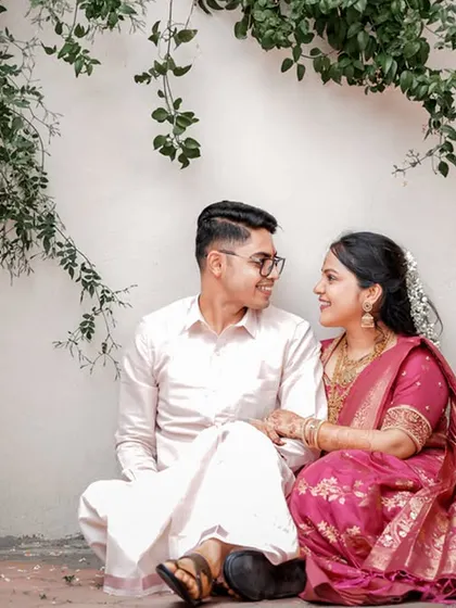 A quiet, seated portrait of the couple sharing a look, framed by delicate hanging vines.