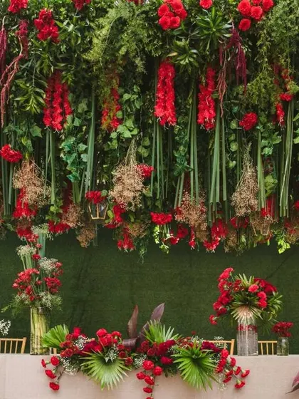 A detailed view of the tablescape, showing how the overhead red floral canopy and the table centerpieces create a cohesive and immersive dining experience.