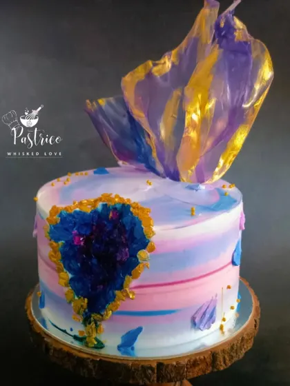 A stunning geode cake with a watercolour effect, a crystallized sugar heart, and a delicate rice paper sail.