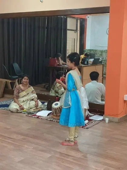 A young student performs for her guru and the tabla player during her practical exam.
