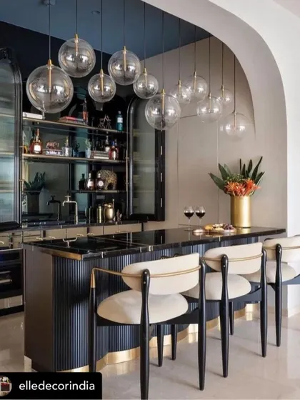 A sophisticated home bar we created, featured in Elle Decor. The design includes a fluted black bar counter, brass accents, and custom bar stools with black wood frames and cream upholstery.