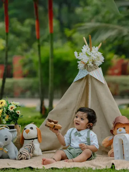 A year of firsts! This little boy enjoys his outdoor birthday bash, surrounded by his favorite toys in a charming picnic setup.