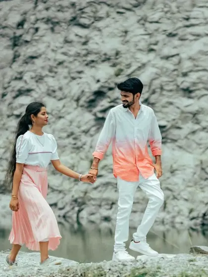 A couple walks hand-in-hand along the edge of a quarry lake. Their casual outfits and the rugged landscape create a beautiful contrast.