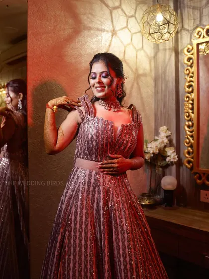 A bride getting ready for her engagement. She smiles, looking at her reflection, her sequined gown sparkling under the warm lights of the dressing room.