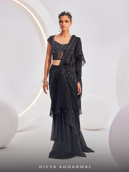 The Nerio Saree Set in classic black. This pre-draped concept saree includes an embellished blouse with a sheer panel, creating a look of sartorial elegance for cocktail gatherings.