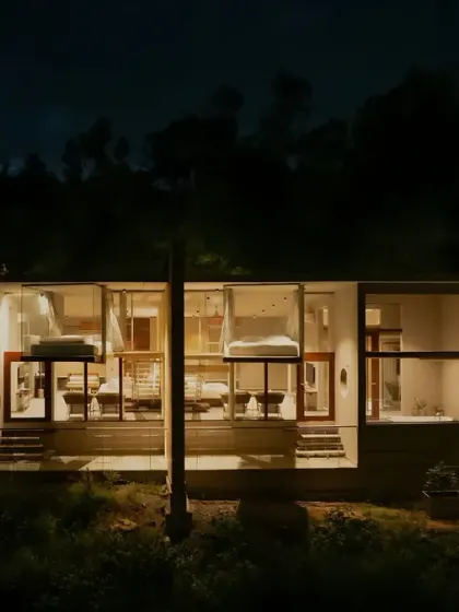 A close-up night view of the resort cottages, where the warm interior light reveals the minimalist design of the bedrooms within.