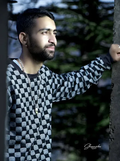 A moody and atmospheric individual portrait. The checkered shirt and the dark, natural setting give this photo a unique and pensive feel.