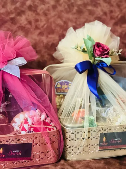 Two festive hampers in ornate metal baskets, wrapped in pink and cream tulle with satin ribbons. Ideal for gifting to clients or employees.