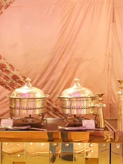 A close-up of our silver chafing dishes and gold decor pieces on a reflective gold buffet counter. This setup is ideal for clients looking for a truly glamorous and royal wedding theme.