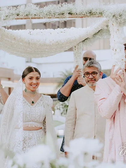 A beautiful shot of the bride walking under the 'phoolon ki chadar' during her entry.