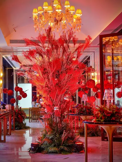 A towering centerpiece made of red-dyed foliage. This dramatic installation served as a major focal point in the room, adding to the bold and eclectic theme.
