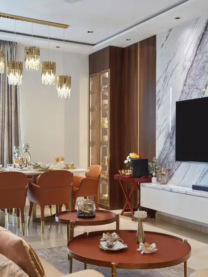 An open-concept living and dining area from a Lodha project, featuring warm terracotta chairs, a sleek crockery unit, and a stunning marble TV wall.