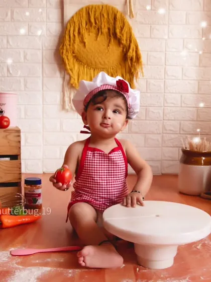 Our little chef is ready to get cooking, holding a tomato before starting her cake smash.