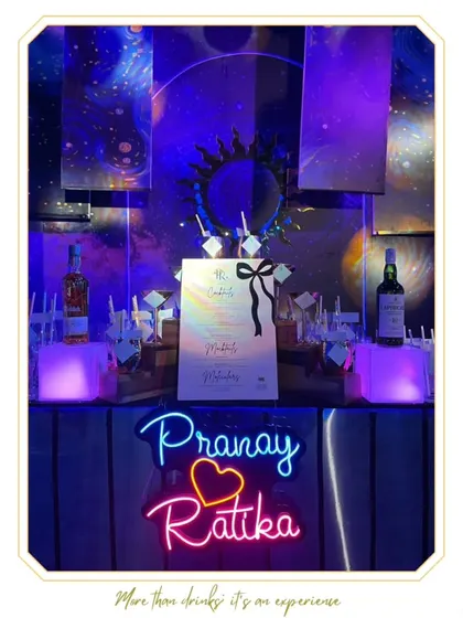 A custom neon sign for "Pranay & Ratika" adds a personal and modern touch to their wedding bar.