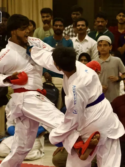 A dynamic exchange during a kumite bout. One of our students lands a clean punch while executing a kick, showing the complex coordination required in sports karate.