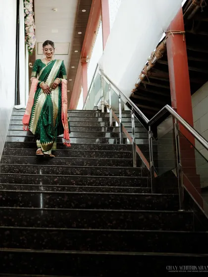 A grand entrance. This shot captures the bride descending the stairs, looking every bit the Maratha queen in her traditional wedding attire.