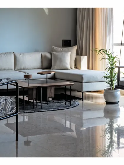 An airy living room from our 'Powai House' project. We designed a plush, light-colored L-shaped sofa to maximize seating in a compact space, pairing it with a sleek coffee table and an indoor swing to create a bright and relaxing atmosphere.