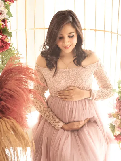 A quiet moment of reflection. The mom-to-be looks down at her bump, seated in our beautifully decorated birdcage chair.