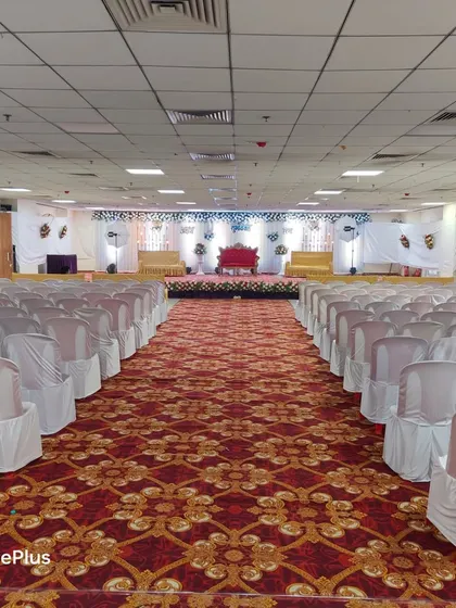 A full view of a large hall prepared for a wedding reception. I ensure all seating is arranged neatly with clean chair covers, creating a uniform and grand look for your event.