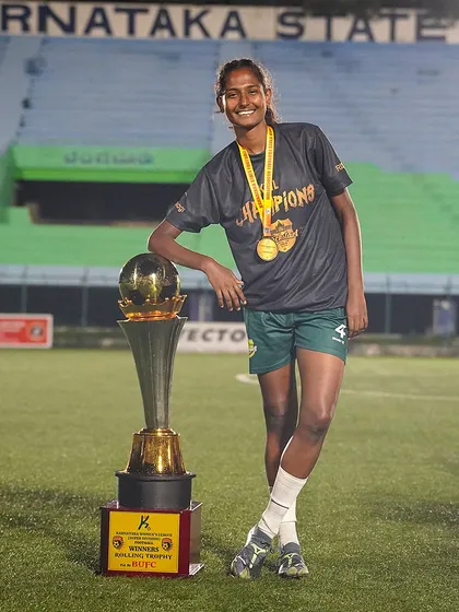 Relaxing with the reward. A victorious player leans casually on the championship trophy, a picture of confidence and accomplishment after a tough season.