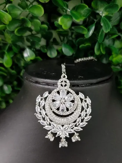 A sparkling American Diamond maang tikka with a floral and crescent design, perfect for a reception look.