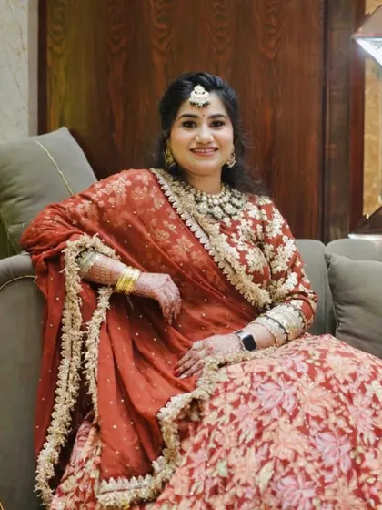 A happy client in a beautiful red and gold lehenga.