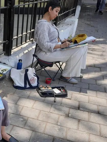Another shot of me sketching on location. You can see my portable setup, including my sketchbook, paints, and foldable chair, which allows me to paint anywhere.