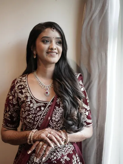 A smiling portrait of Chaithanya by the window. The natural light highlights the soft, subtle makeup, creating a fresh and radiant reception look.