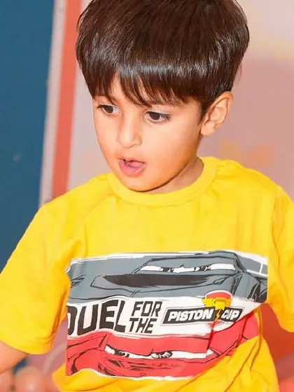 A boy in a Cars t-shirt enjoys playing in the ball pit.