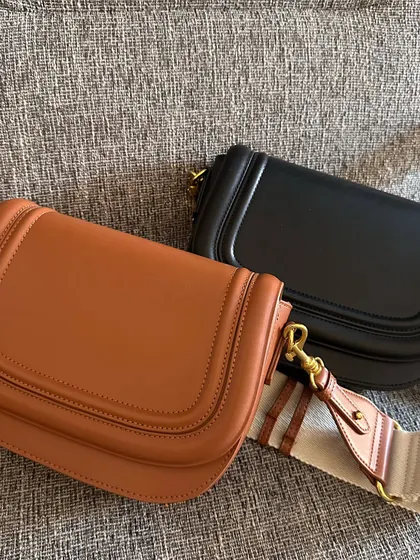 The brown and black Noble bags displayed together. This view highlights the curved saddle shape and the clean, structured lines of the design.