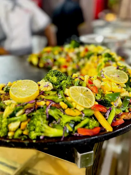 A beautiful display of the English Vinglish Chaat on a large tawa, garnished with fresh lemon slices. The colors of the vegetables make it incredibly appealing.