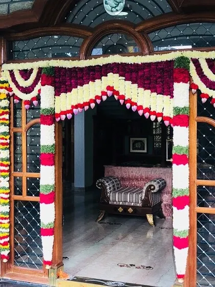 A classic housewarming door decoration with garlands of velvet-red, white, and green flowers. This traditional design is perfect for welcoming guests into your new home.