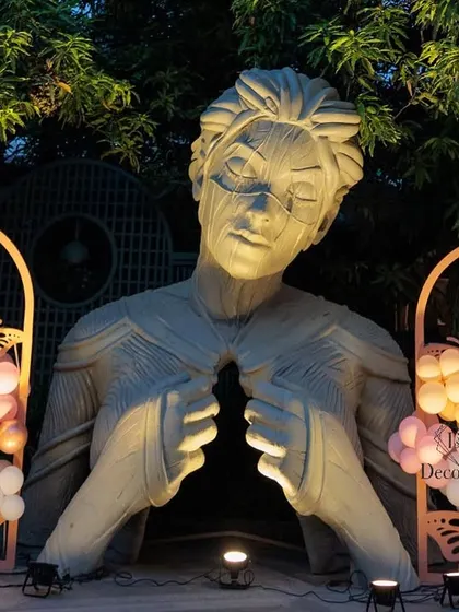 A night view of the decorated sculpture, where uplighting adds drama and highlights the intricate details of both the art and our custom butterfly-themed panels.