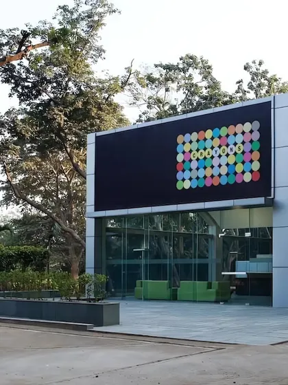 A closer view of the entrance to the Okhla office project. The design juxtaposes the sleek, modern glass facade with the lush, mature trees of the site, reflecting our philosophy of designing in harmony with the context.