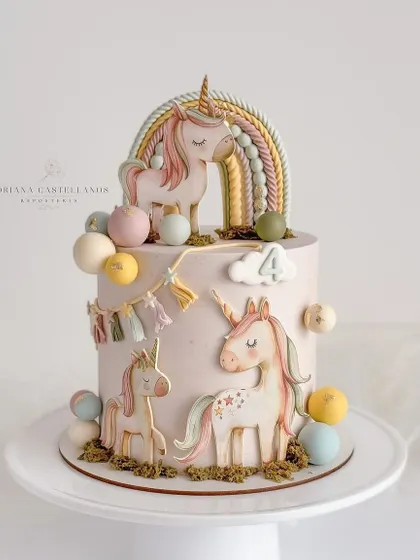 An artistic and rustic unicorn-themed cake. This design features beautifully painted unicorns and a boho-style rainbow, perfect for a unique celebration.