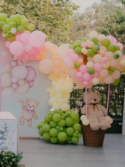 A cute teddy bear in a hot air balloon made of balloons adds a whimsical touch to Inaaya's half-birthday celebration.