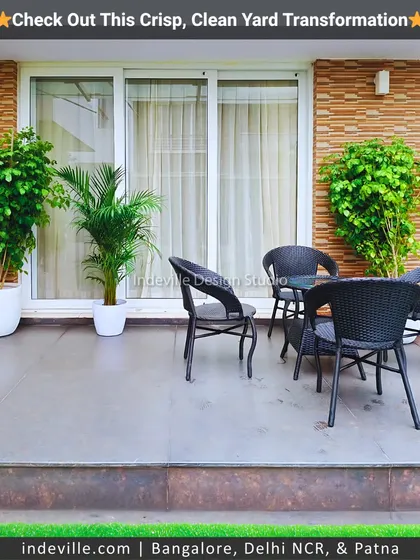 A simple and elegant patio area in a backyard. I used modern black rattan chairs and potted plants to create a comfortable seating area that seamlessly connects with the garden.