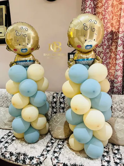 Adorable balloon pillars for a baby boy's welcome home party. These feature columns of pastel blue and yellow balloons topped with large foil balloons shaped like a baby.