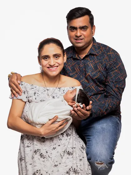 A happy family portrait where both parents embrace their newborn. This shot captures the joy and completeness a new baby brings to a family, perfect for sharing with loved ones.