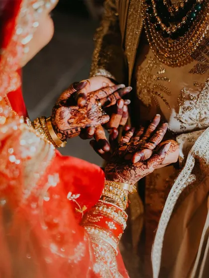 A close-up on the hands during a wedding ritual. The intricate henna and the gentle touch tell a story of tradition, commitment, and the beginning of a shared life.