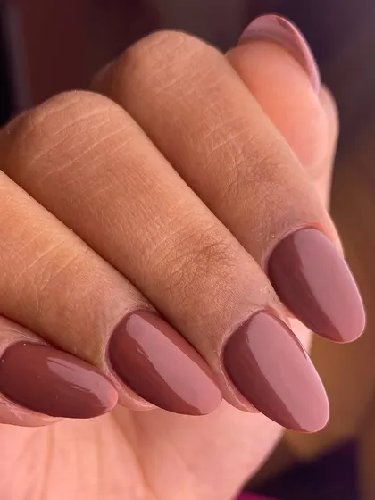 A sophisticated and versatile solid color manicure. These perfectly shaped almond nails are coated in a rich, glossy mauve-brown polish, ideal for a professional yet stylish look.