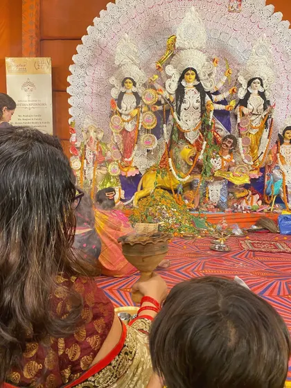 A devotee performs the Dhunuchi Naach, a traditional dance with an earthen incense burner, in front of the Durga idol during Durga Puja celebrations in Gurgaon.