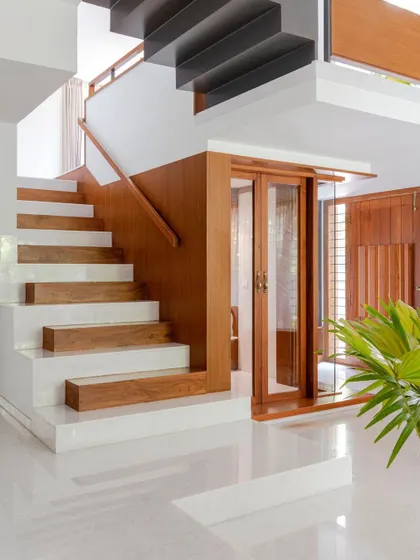 The main staircase in the Copper House is crafted with alternating steps of white marble and solid teak wood. This detail borrows material traits from the adjacent prayer room and marks the beginning of the home's vertical circulation journey.